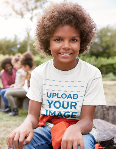 T-Shirt Mockup of a Happy Boy Sitting on a Tree Trunk 