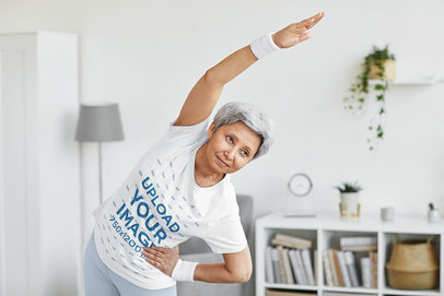 T-Shirt Mockup Featuring a Senior Short-Haired Woman Stretching at Home 