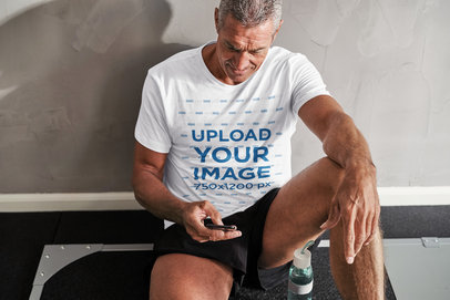 Activewear Mockup Featuring a Senior Man Wearing a T-Shirt and Checking His Phone 