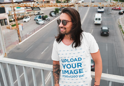 T-Shirt Mockup of a Carefree Tattooed Man Posing on an Urban Bridge