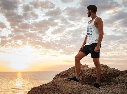Tank Top Mockup of an Athletic Man Standing on a Rock at the Beach