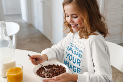 Mockup of a Girl with a Crewneck Sweatshirt Having Breakfast