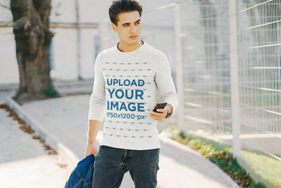 Mockup of a Man with a Heather Long-Sleeve Tee Checking His Phone