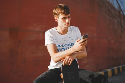 T-Shirt Mockup of a Skater Man Staring at His Phone