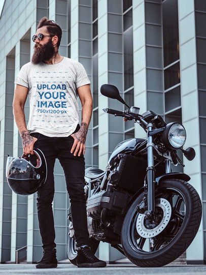 T-Shirt Mockup of a Man with a Thick Beard Posing Next to a Motorbike