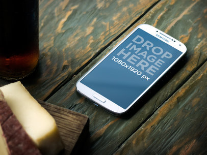 Mockup of a Samsung Galaxy Lying in Portrait Position over a Bistro Table