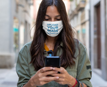 Face Mask Mockup of a Woman Checking Her Phone on the Street