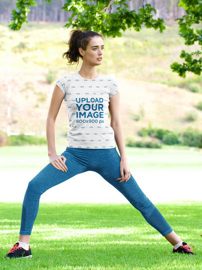 Sublimated T-Shirt Mockup Featuring a Woman Stretching at a Park 