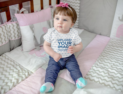 Mockup of a Baby Girl Sitting In Her Crib While Wearing a Onesie