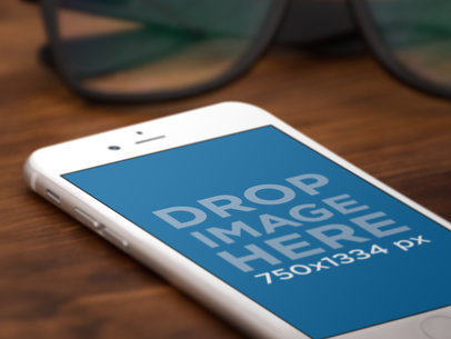 Close-up Mockup of an iPhone 6 Lying Over a Wooden Table Next to Glasses a12703