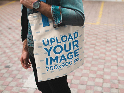 Tote Bag Mockup of a Man Carrying a Bag While Standing Near Yellow Lines on the Floor