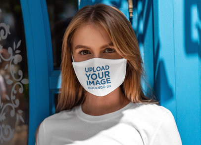 Sublimated Face Mask Mockup Featuring a Woman Posing Against a Blue Door 4891-el1