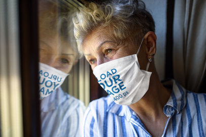 Face Mask Mockup of a Senior Woman Looking Through a Window