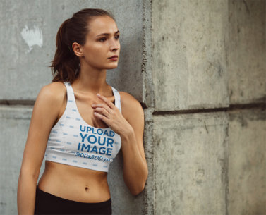 Sports Bra Mockup Featuring a Woman Leaning Against a Wall 