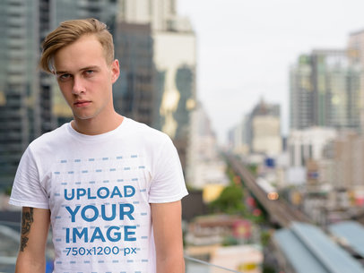 T-Shirt Mockup of a Serious Young Man Posing in the City