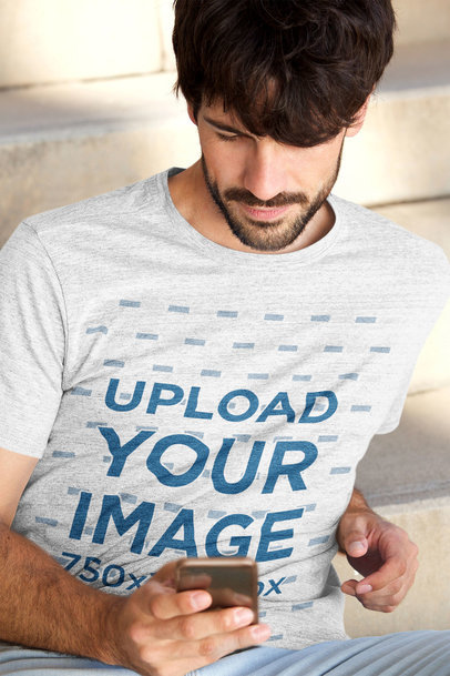 Heather T-Shirt Mockup Featuring a Bearded Man Checking His Phone 