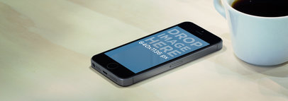 Mockup of an iPhone 5S in Portrait Position Next to a Hot Beverage