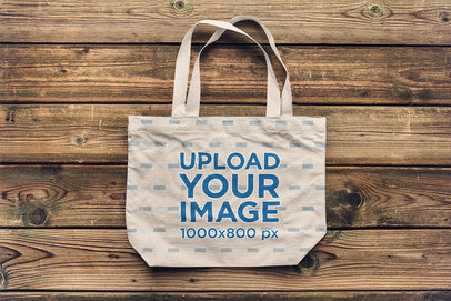 Mockup of a Flat Laid Tote Bag over a Wooden Surface