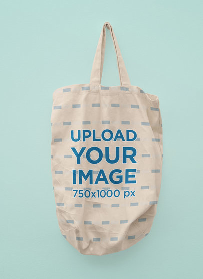 Mockup of a Sublimated Tote Bag Hanging Against a Customizable Background 