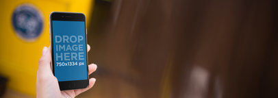 Mockup Of A Woman's Left Hand Holding A Black iPhone