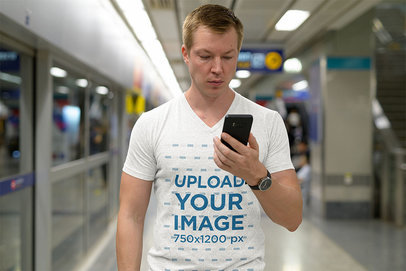 T-Shirt Mockup of a Man Looking at His Phone at the Subway Station