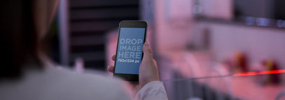 Over Shoulder Mockup Of A Girl Looking At Her iPhone 6 While At A Diner Restaurant With Red Lights On The Background a13998wide