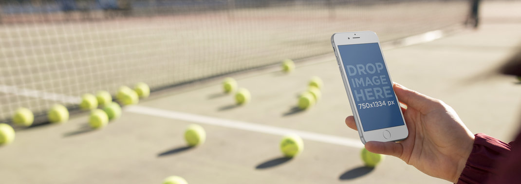 Woman Holding An iPhone While At A Tennis Court Mockup