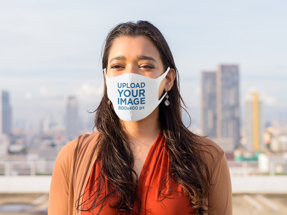 Face Mask Mockup of a Long-Haired Woman Posing Against a City Skyline 