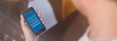 Over Shoulder Mockup Featuring a Man Holding a Black iPhone in His Hand 