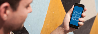Mockup of a Young Man Using His Smartphone Next to a Colorful Wall 14125w