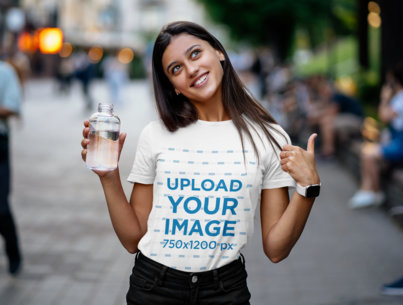 T-Shirt Mockup Featuring a Happy Young Woman Holding a Bottle of Water 