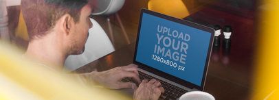 Through The Window View Mockup of a Young Man Using His MacBook Pro