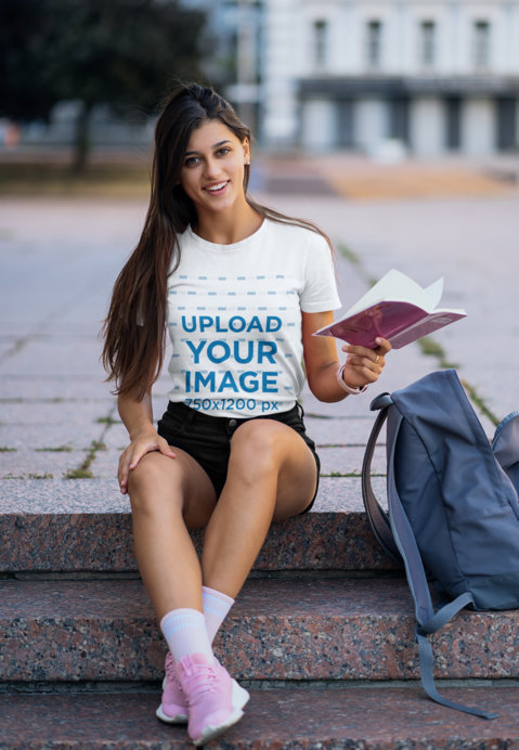 T-Shirt Mockup of a College Student Holding a Book 