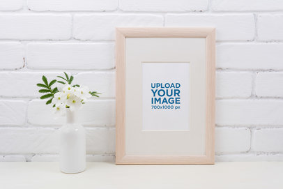 Mockup of a Small Art Print Placed Against a White Wall