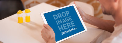 Over Shoulder iPad Mockup Featuring a Man Sitting at a White Table 14123