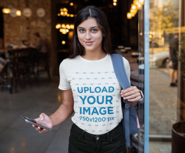 T-Shirt Mockup Featuring a Young Woman Holding Her Phone