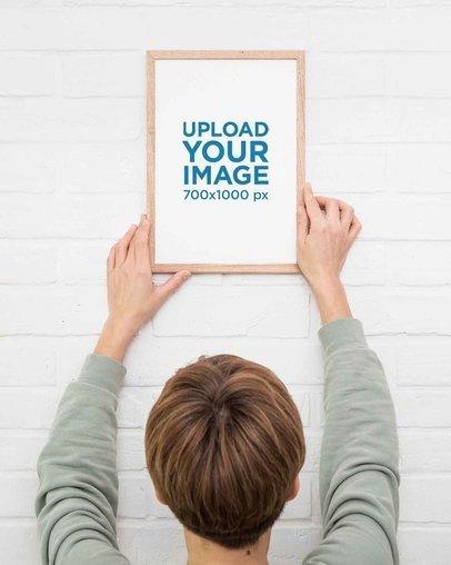 Mockup of a Man Hanging an Art Print on the Wall