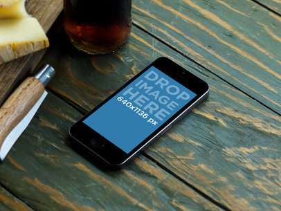 Mockup of an iPhone 5S over a Restaurant Wooden Table