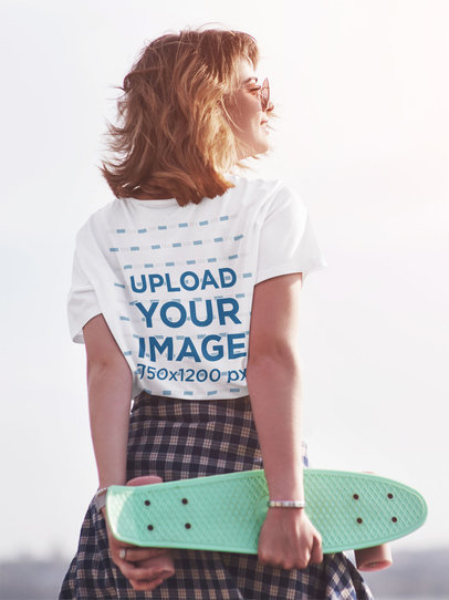 Back-View T-Shirt Mockup of a Woman Holding a Penny Skateboard