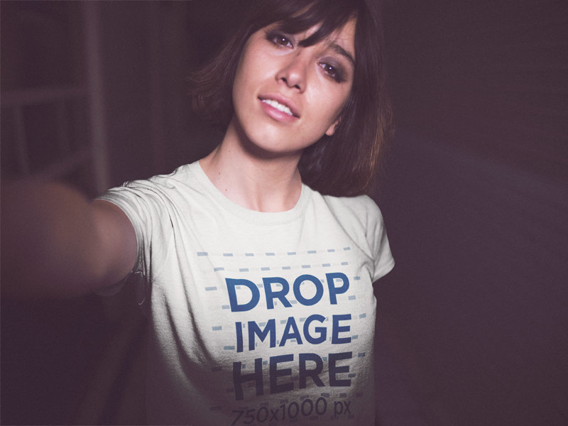 Mockup Selfie of a Young Pretty Woman With Short Hair Wearing a T-Shirt While in the City at Night