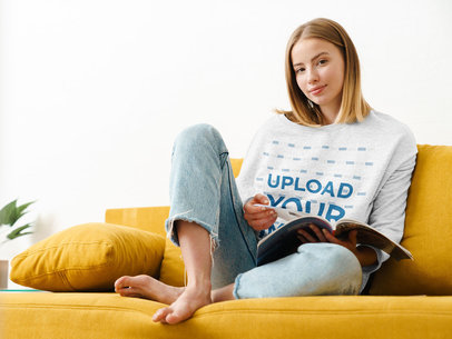 Mockup Featuring a Woman with a Heathered Sweatshirt Reading on the Couch