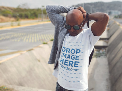 Mockup of a Man Wearing a Round Neck Tshirt and Steampunk Sunglasses While Outside of the City Template