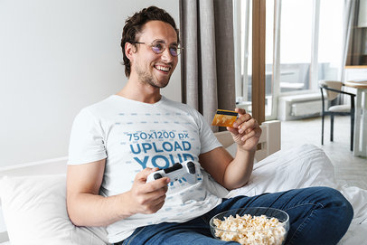 T-Shirt Mockup of a Man Chilling Playing Games at Home