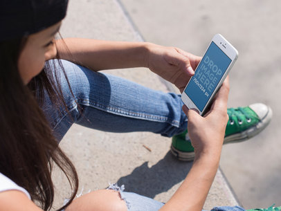 Mockup of a Young Woman Using Her iPhone 7 While Sitting Down at the Skate Park