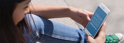 Mockup of a Young Woman Using Her iPhone 6 While Sitting Down at the Skate Park