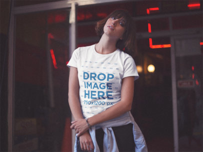 Young Woman Wearing a Round Neck Tee While Near a Closed Store with Red Lights Mockup