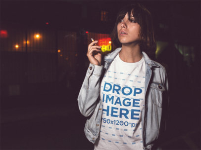 Trendy Woman Smoking in the City at Night While Wearing a Round Neck Tshirt with a Denim Jacket On Top