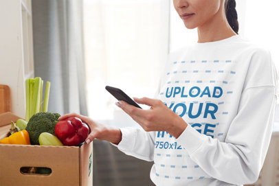 Sweatshirt Mockup Featuring a Woman with a Vegetables Box at Home