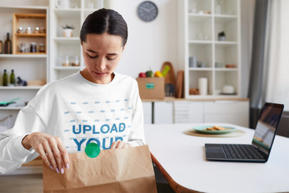 Sweatshirt Mockup Featuring a Woman Opening a Food Bag at Home