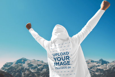Hoodie Mockup Featuring an Excited Man Raising His Arms in the Mountains 